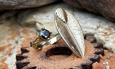 A 14k gold plated ring made with a leaf shape with a small black CZ  crystal