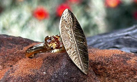 A 14k gold plated ring made with a leaf shape with a small champagne CZ crystal