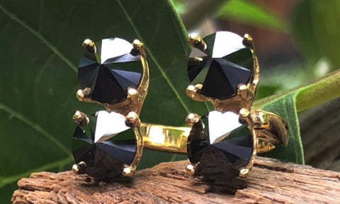 front view of a four-stone gold plated ring with black CZ crystals set on reverse