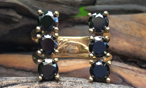 front view of a six-stone gold plated ring with black CZ crystals