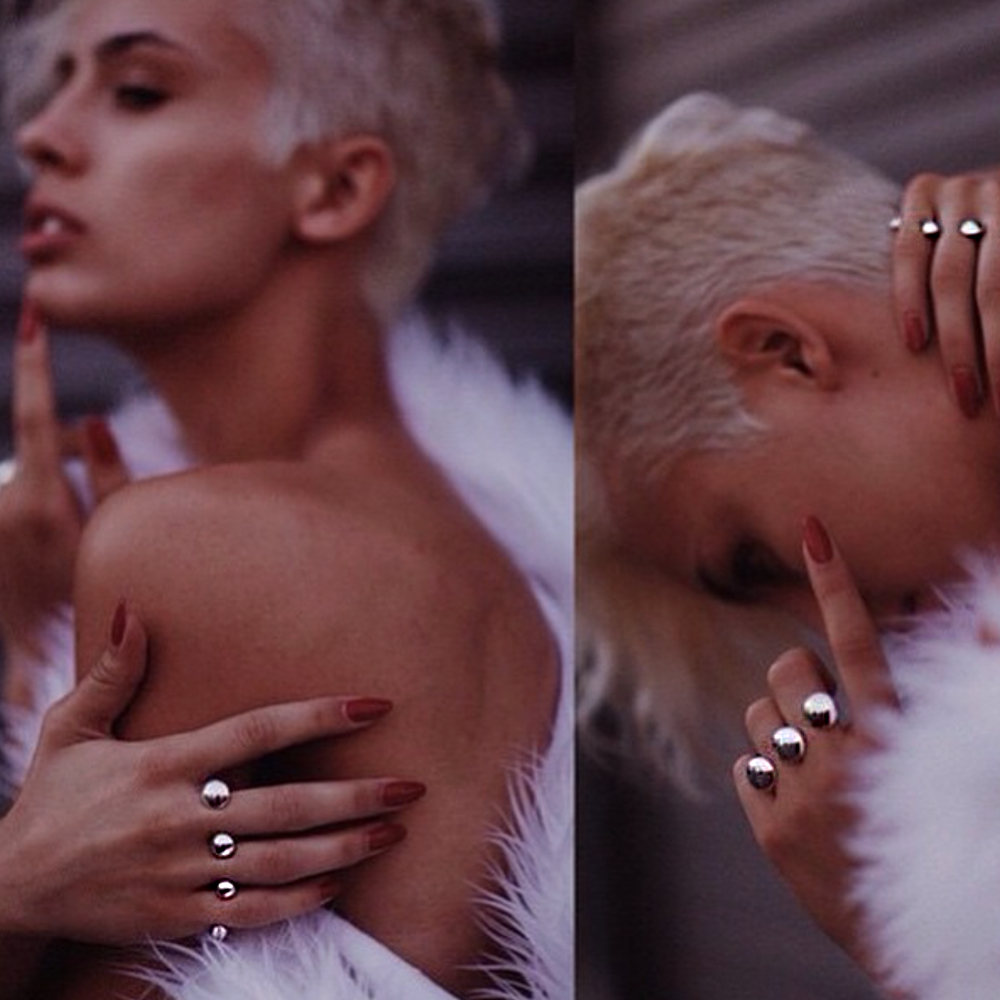 Close-up of a woman with platinum blonde hair and a white faux-fur garment, wearing Valou silver rings on both hands