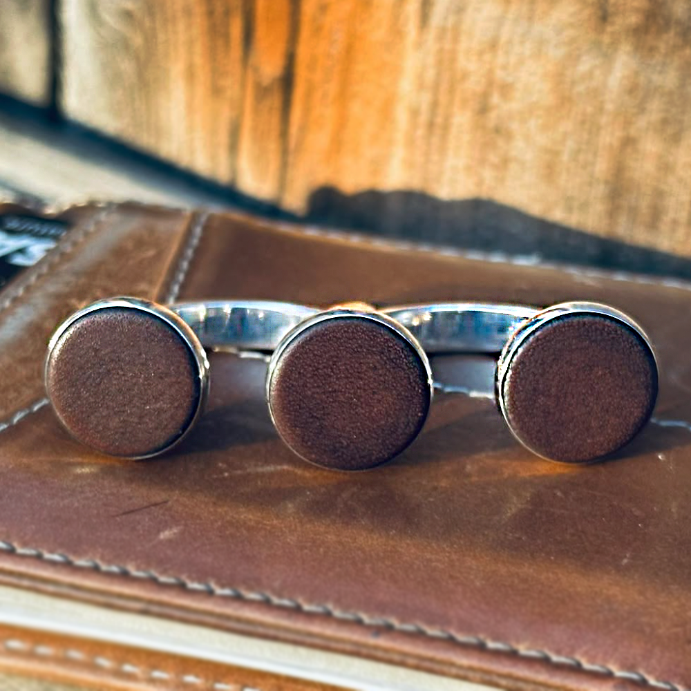 Brown leather and silver 3cap ring placed over a leather wallet