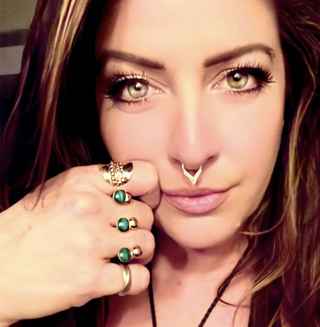 Close-up of a woman wearing a gold double stack of Valou 3cap rings and a gold septum ring.