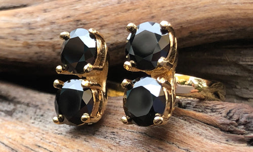side view of a four-stone gold plated ring with black CZ crystals 