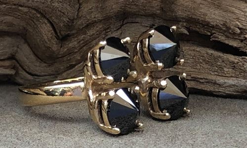 side view of a four-stone gold plated ring with black CZ crystals set on reverse